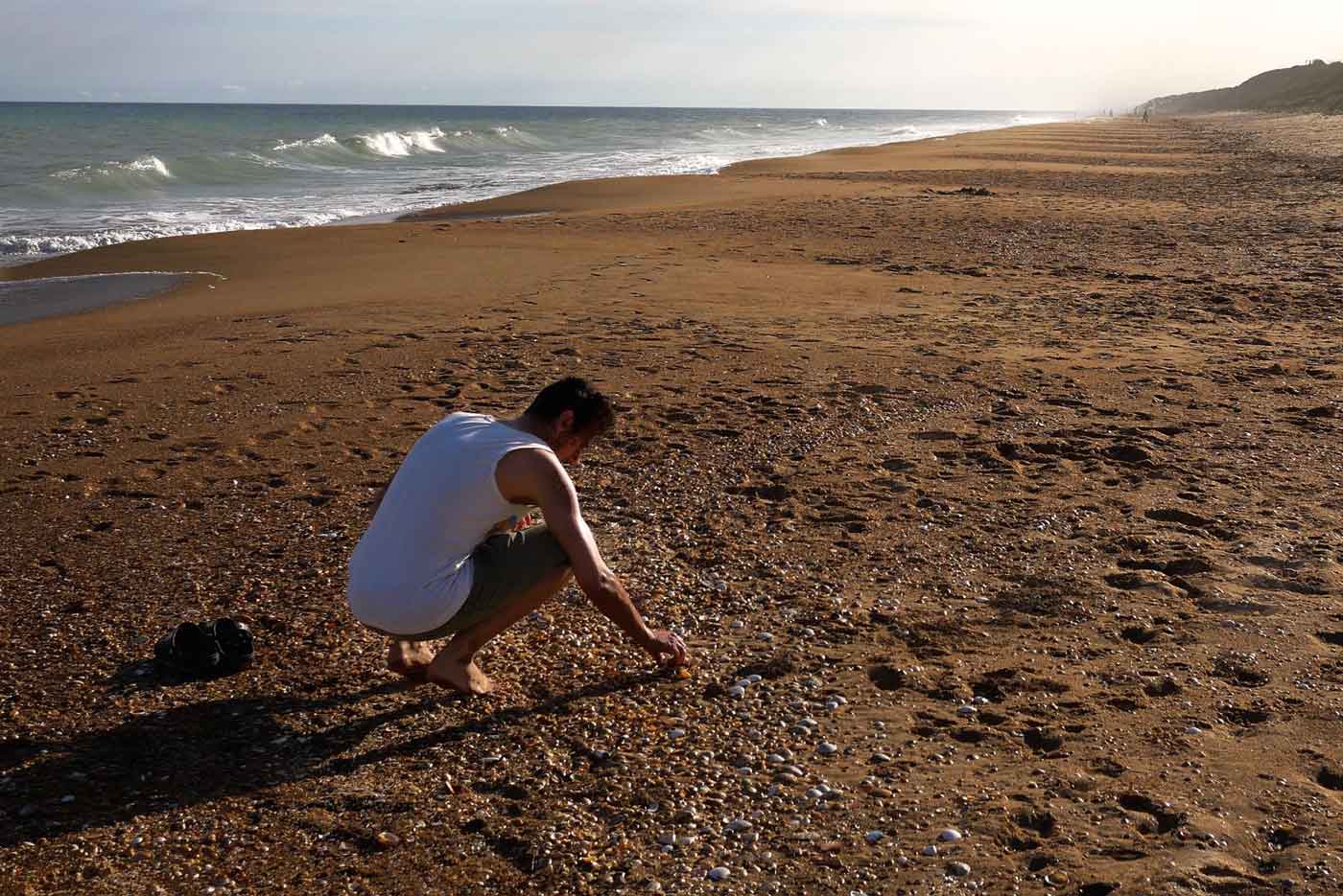 Chris sammelt in einem stillen Moment Muscheln am weiten Strand