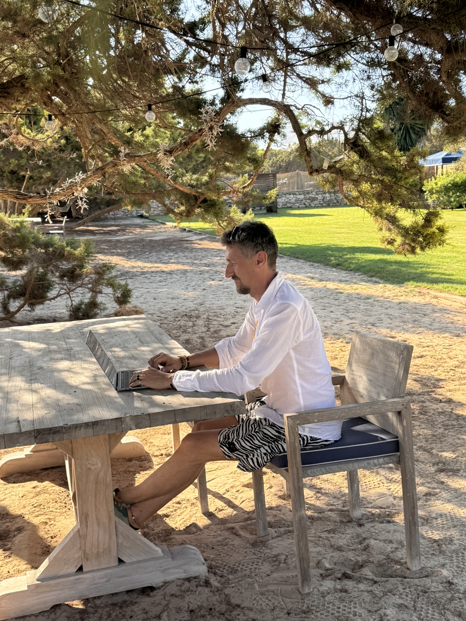 Chris working outdoors under old trees on his laptop