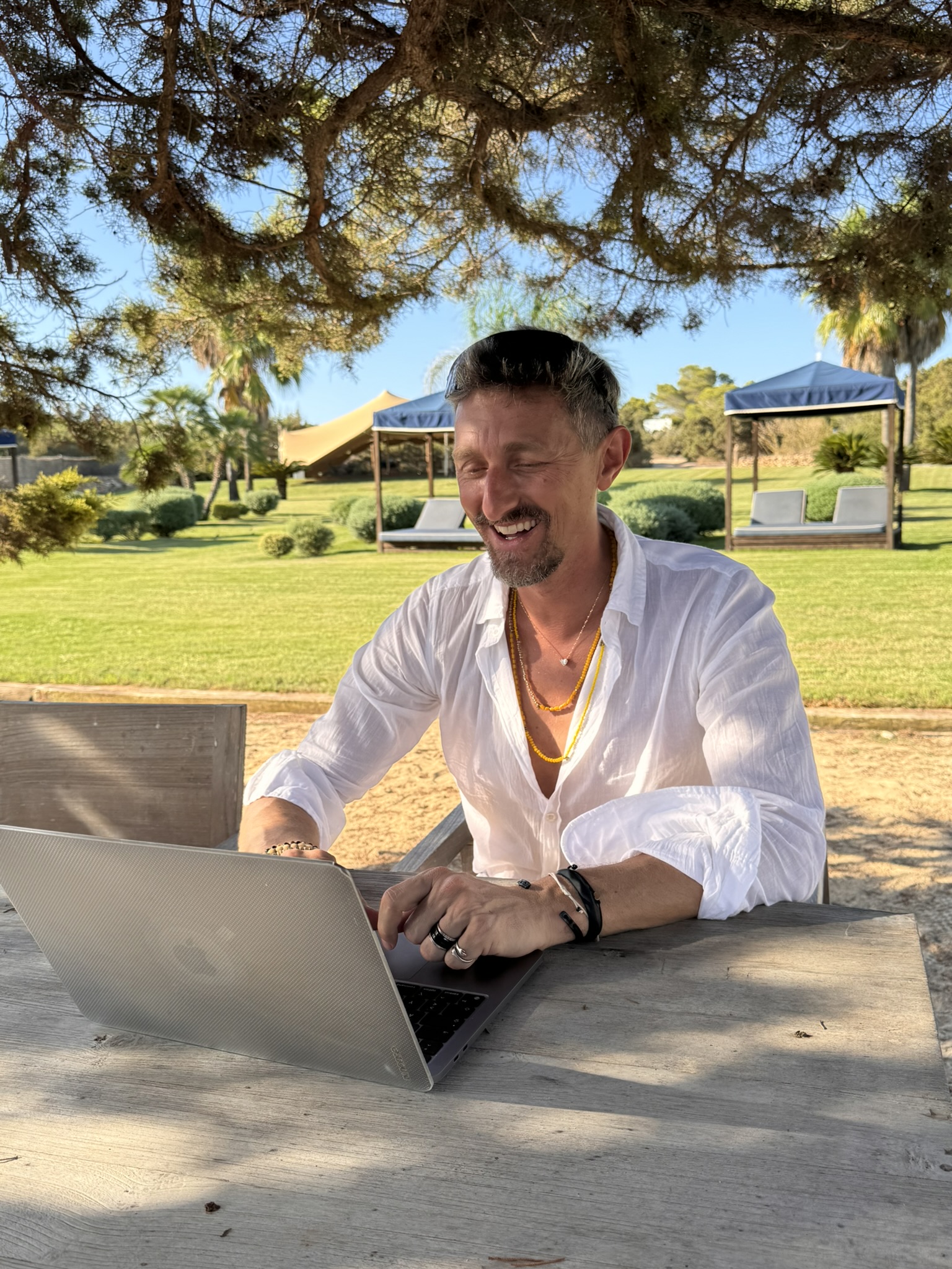 Chris laughing during an online coaching session on his laptop in a Mediterranean garden