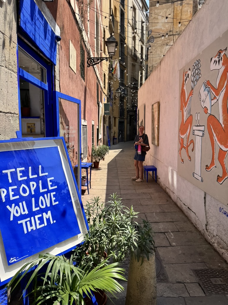 Blaues Schild mit den Worten Tell people you love them vor einer Tür in einer schmalen Gasse
