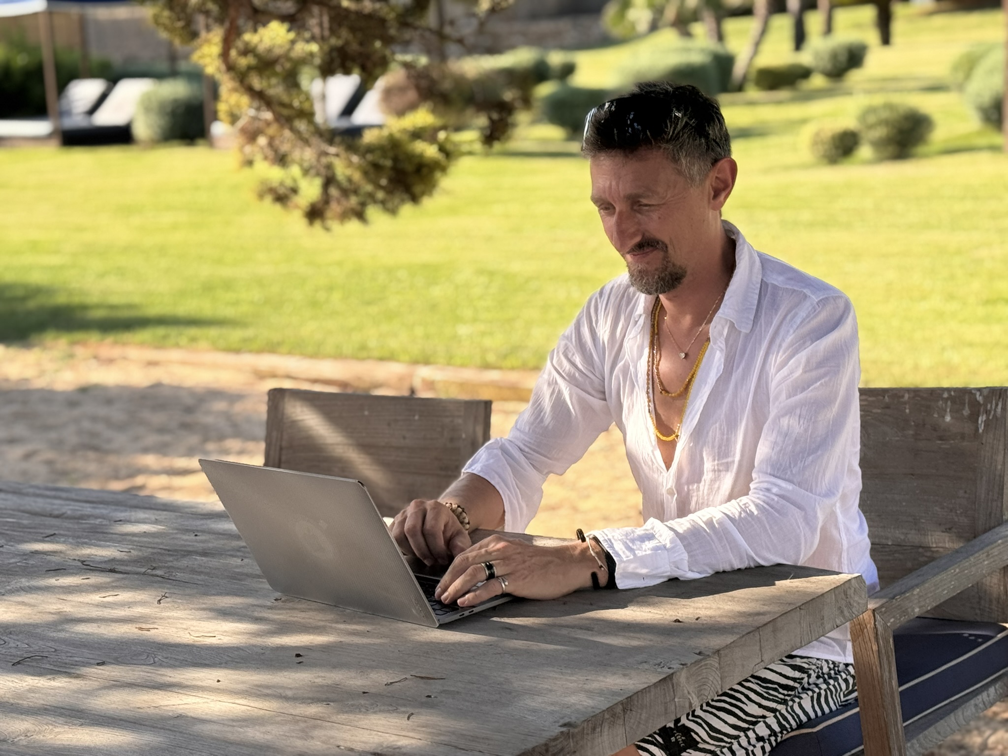 Chris arbeitet unter alten Bäumen konzentriert am Laptop